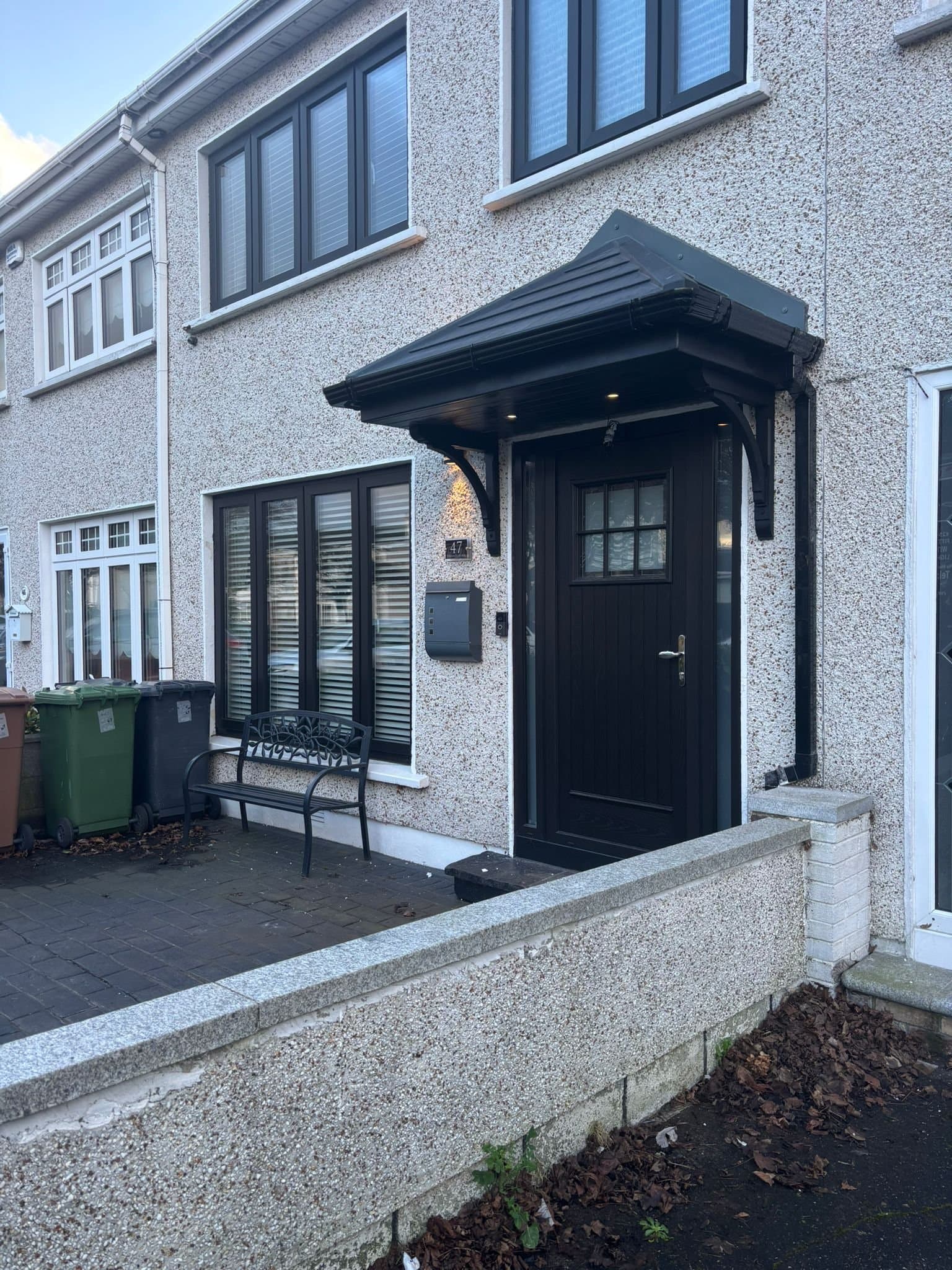 Black door canopy with integrated downlights on terraced house
