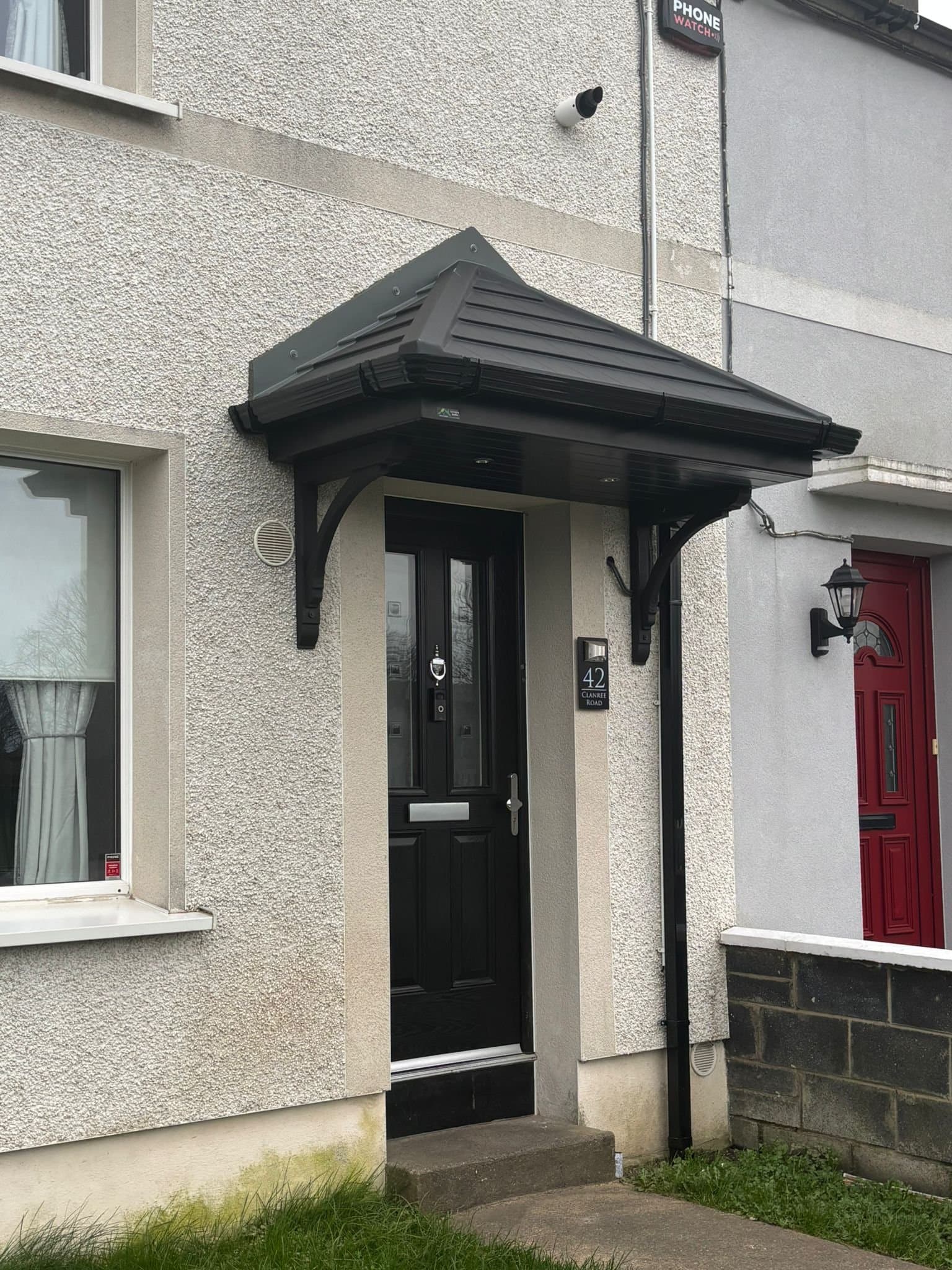 Black hip roof door canopy with bracket supports on terraced house in Dublin