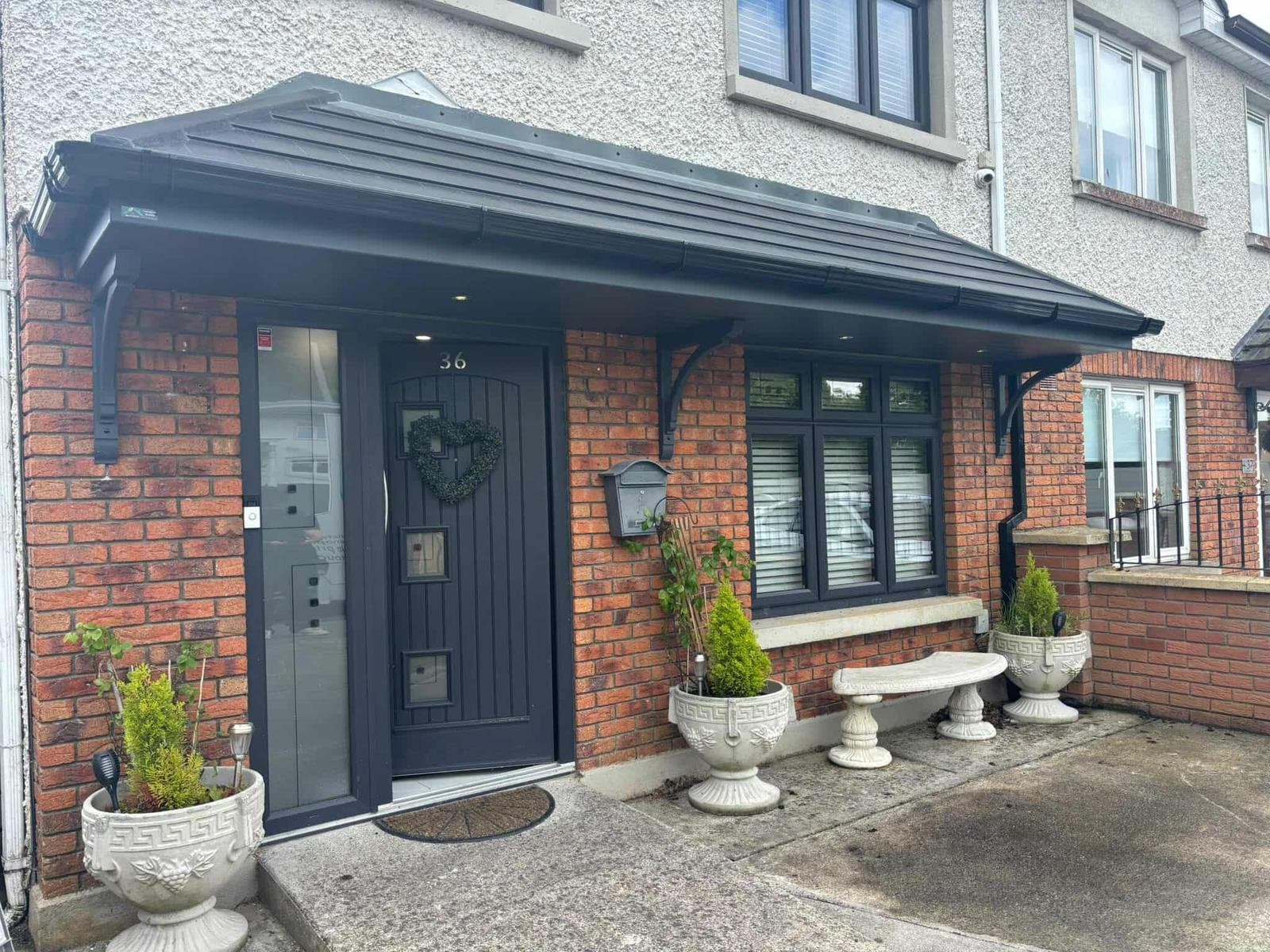Close-up of double hip door canopy with downlights on red brick semi-detached house