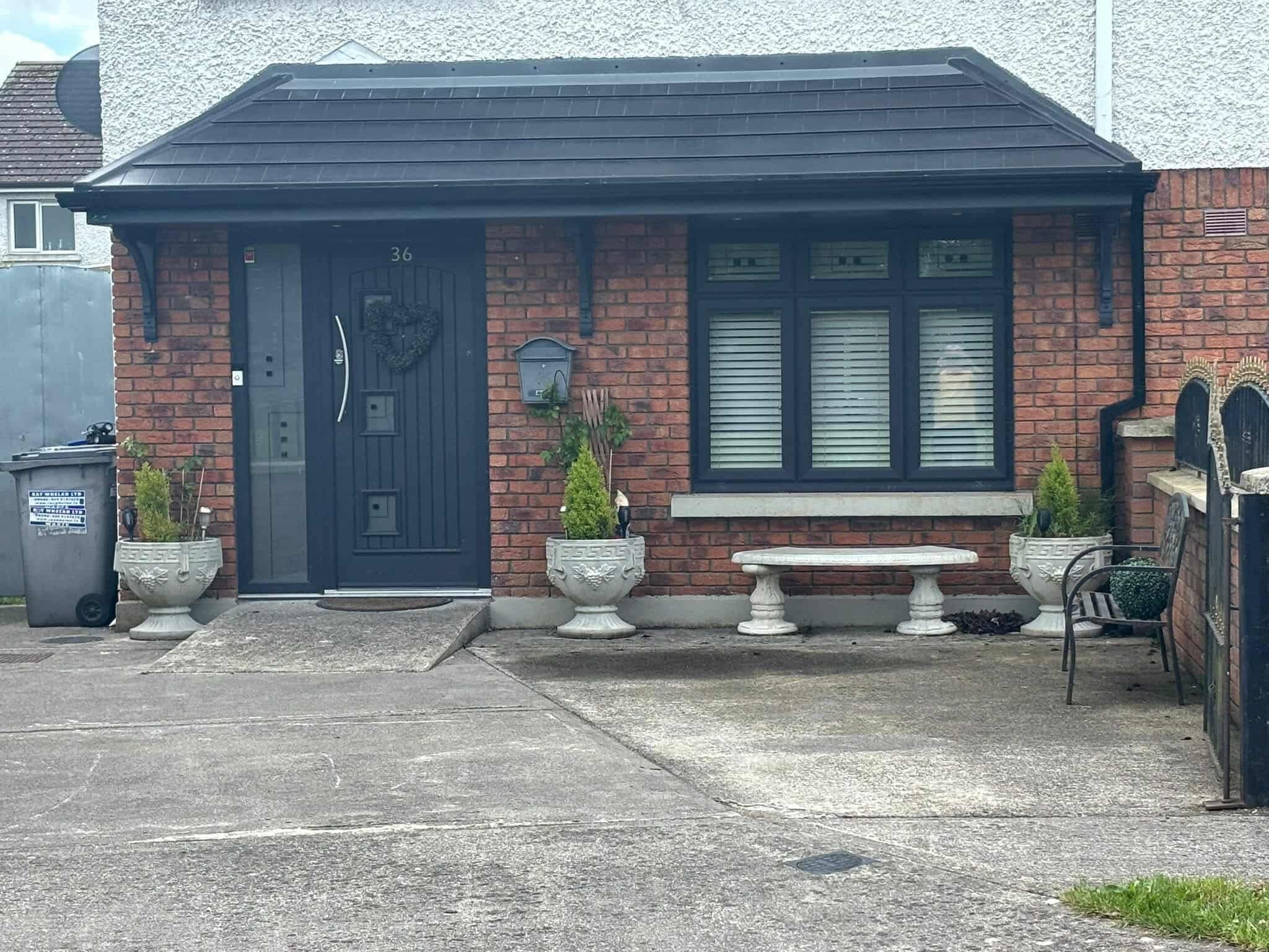 Wide double hip canopy covering full frontage of brick terraced house