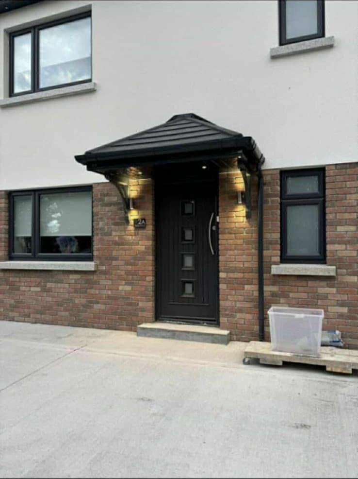 Hip roof door canopy with warm wall lights on brick facade house