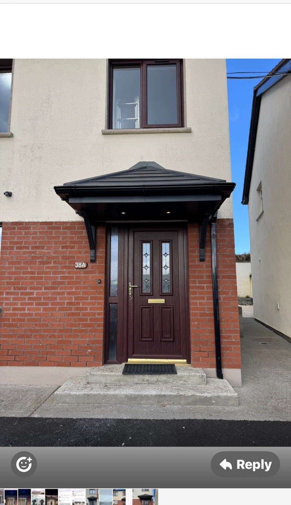 Hip roof door canopy over brown front door on red brick end-of-terrace house