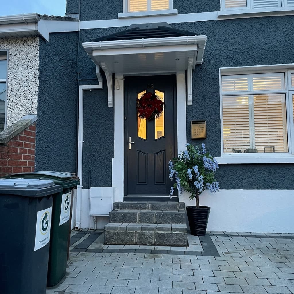 Portico canopy on blue rendered house with Christmas wreath at dusk