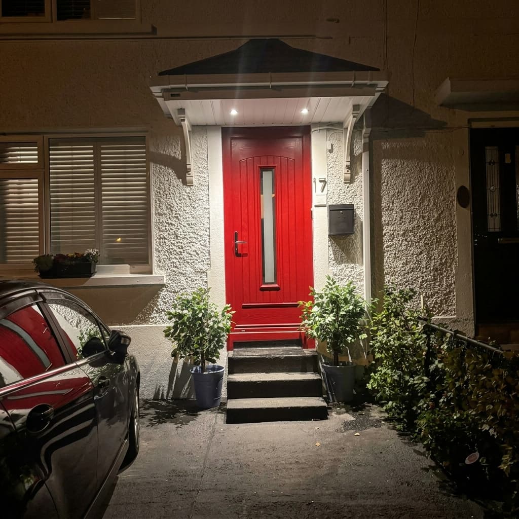 White hipped canopy with downlights illuminating red front door at night